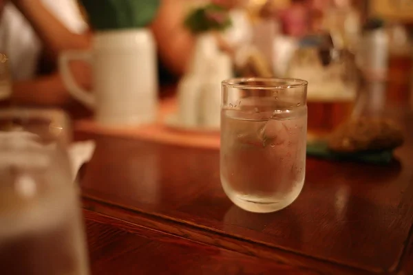 Um copo de água fica em uma mesa de madeira em um restaurante — Fotografia de Stock