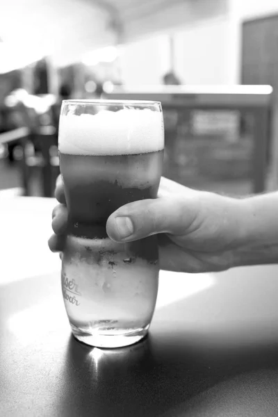 Кружка пива на столе в мужской руке в пабе — стоковое фото