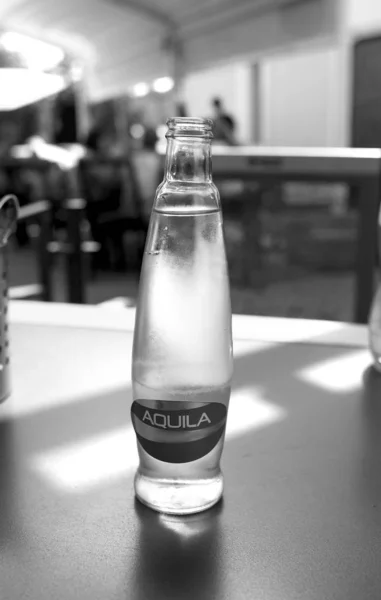 Una botella de vidrio de agua fría mineral se encuentra sobre una mesa en un café — Foto de Stock