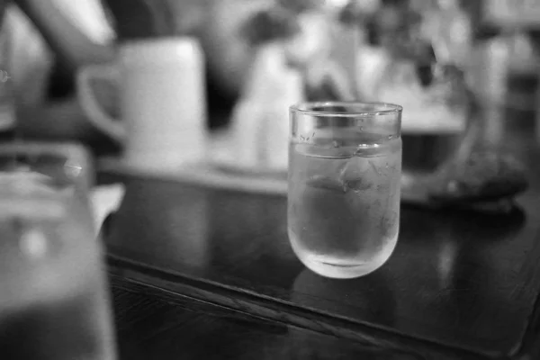 A glass of water stands on a wooden table in a restaurant — ストック写真
