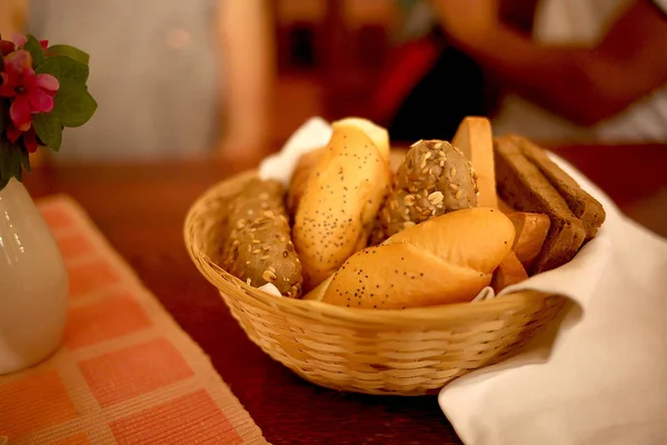 Bullar och bröd i korg på bord i restaurang — Stockfoto