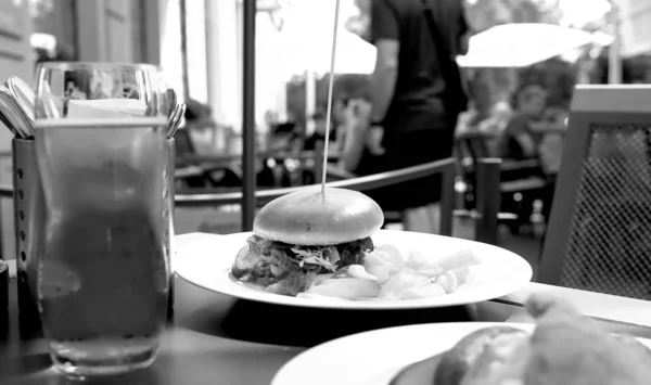 Burger with meat and cheese and pickles on a plate in a restaurant — Stock Photo, Image