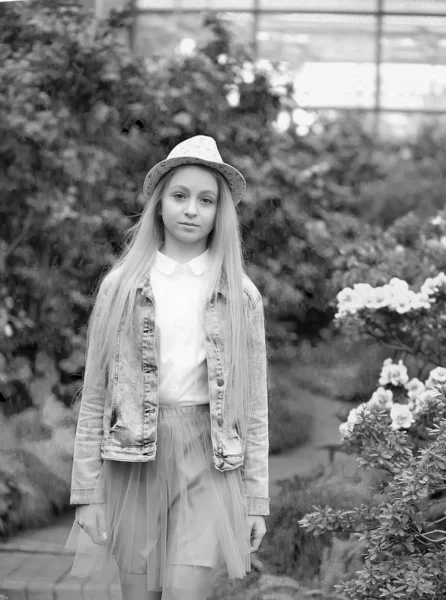 Giovane ragazza con lunghi capelli bianchi in un cappello e una giacca di jeans cammina in giardino — Foto Stock