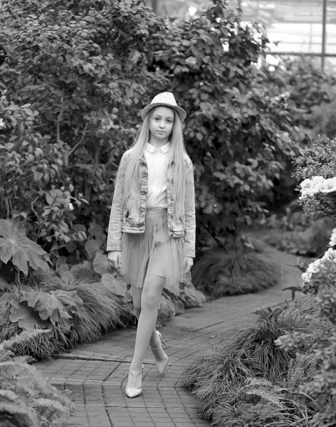 Muchacha joven con el pelo blanco largo en un sombrero y una chaqueta de mezclilla camina en el jardín —  Fotos de Stock