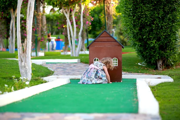 Menina jogando perto de uma pequena casa marrom de madeira no parque infantil — Fotografia de Stock