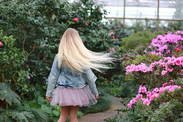Dívka s dlouhými bílými vlasy v džínové bundě chodí v kvetoucí — Stock fotografie