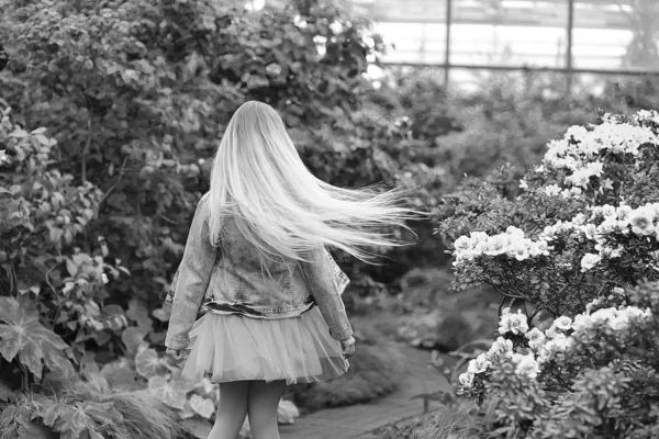 Дівчина з довгим білим волоссям в джинсовій куртці ходить у квітучому — стокове фото