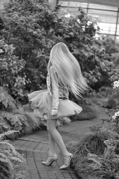 Girl with long white hair in a denim jacket walks in a flowering — Stock Photo, Image