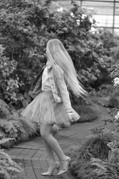 Girl with long white hair in a denim jacket walks in a flowering — Stock Photo, Image