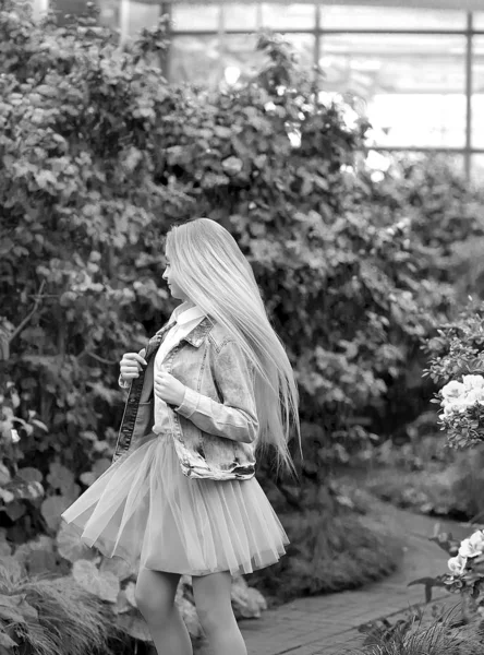 Chica con el pelo largo y blanco en una chaqueta de mezclilla camina en una floración — Foto de Stock