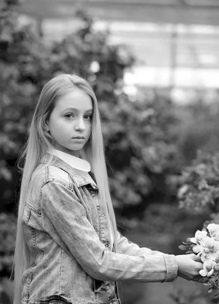 Meisje met lang wit haar in een spijkerjasje loopt in een bloeiende — Stockfoto