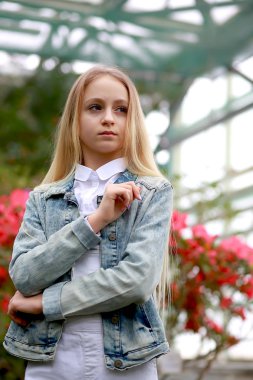 Kot ceketli, uzun beyaz saçlı genç kız yürüyor. 