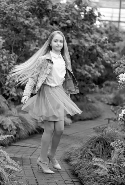Meisje met lang wit haar in een spijkerjasje loopt in een bloeiende — Stockfoto