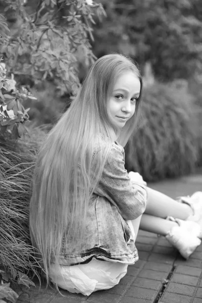 Ung flicka med långt vitt hår och en jeansjacka sitter med henne — Stockfoto