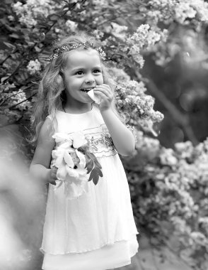 Beyaz elbiseli küçük bir kız bahar botanik bahçesinde yürüyor.