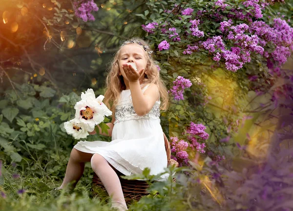Beyaz elbiseli küçük bir kız bahar botanik bahçesinde yürüyor. — Stok fotoğraf