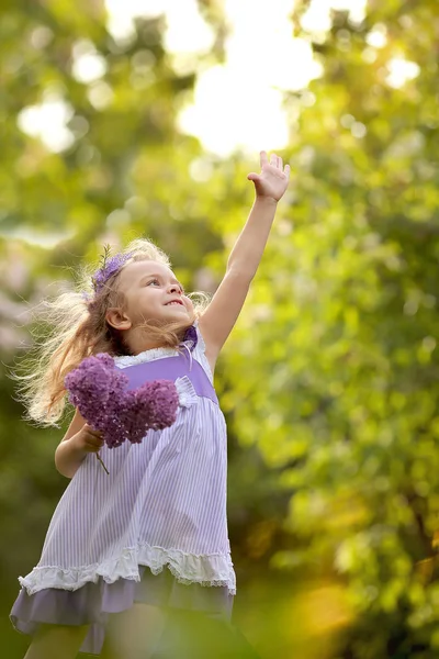 小女孩走在春天的植物园里，那里有淡紫色的叶子 — 图库照片