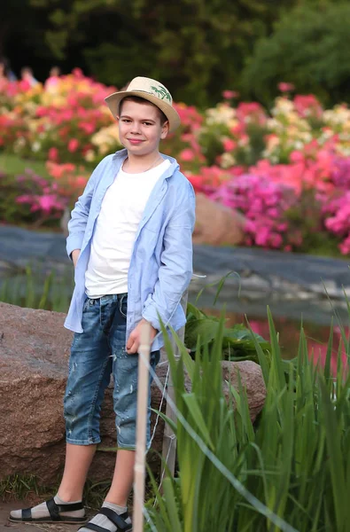 Chlapec v klobouku kráčí v jarní botanické zahradě, kde květina — Stock fotografie