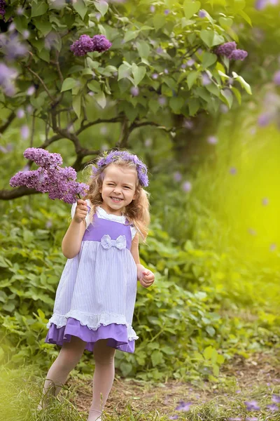 Little girl in a white dress walks in the spring botanical garden — Stock Photo, Image