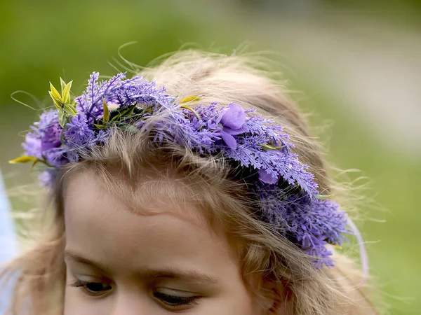 Hermosa corona de lila en la cabeza de una niña rubia —  Fotos de Stock