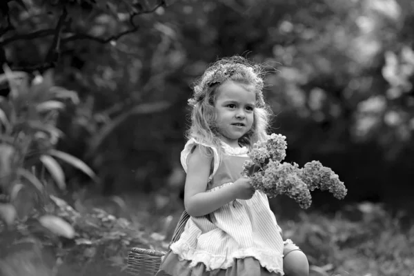Маленька дівчинка в білій сукні гуляє в весняному ботанічному саду — стокове фото