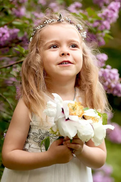 Kleines Mädchen im weißen Kleid spaziert in der frühlingshaften botanischen Garde — Stockfoto