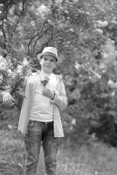 Мальчик в шляпе гуляет в весеннем ботаническом саду, где цветок — стоковое фото