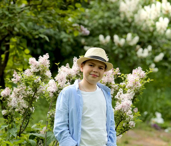 Een jongen met een hoed wandelt in de lente botanische tuin — Stockfoto