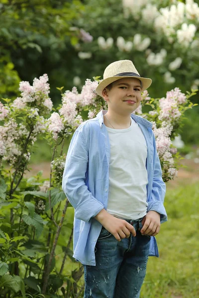Chlapec v klobouku kráčí po jarní botanické zahradě — Stock fotografie