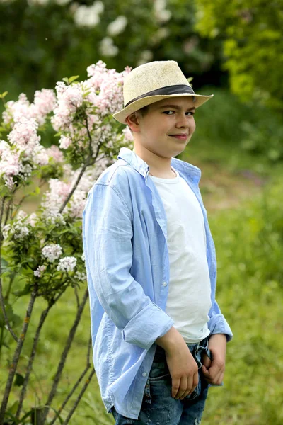 Een jongen met een hoed loopt in de lente botanische tuin waar bloem — Stockfoto