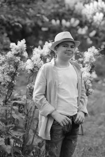 A boy in a hat walks in the spring botanical garden where flower — ストック写真