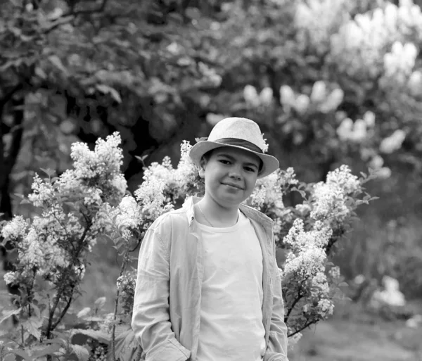 Een jongen met een hoed loopt in de lente botanische tuin waar bloem — Stockfoto