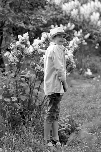 Un niño en un sombrero camina en el jardín botánico de primavera — Foto de Stock