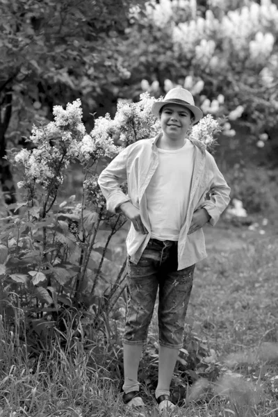 Een jongen met een hoed wandelt in de lente botanische tuin — Stockfoto