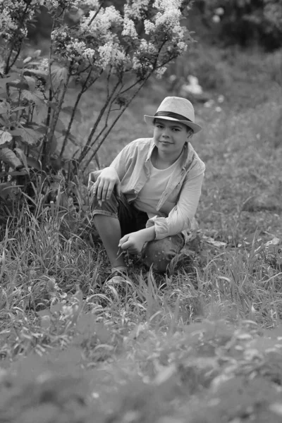 Een jongen met een hoed wandelt in de lente botanische tuin — Stockfoto