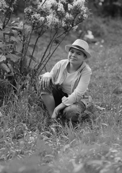 A boy in a hat walks in the spring botanical garden where flower — ストック写真