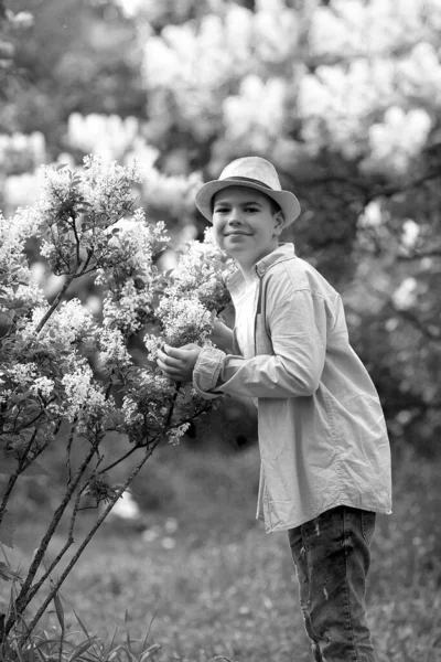 Un garçon dans un chapeau se promène dans le jardin botanique de printemps où fleur — Photo