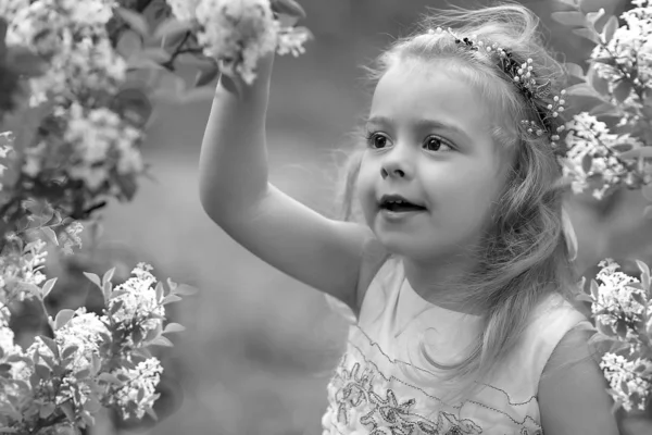Klein meisje in een witte jurk wandelingen in de lente botanische tuin — Stockfoto