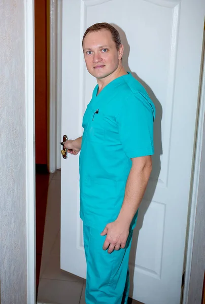 Mladý atraktivní lékař v lékařském obleku u dveří — Stock fotografie