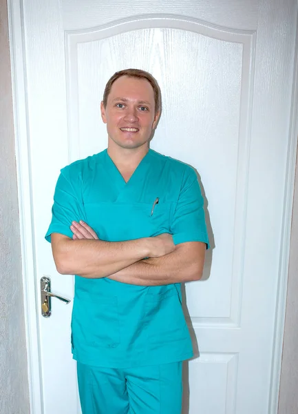 Mladý atraktivní lékař v lékařském obleku u dveří — Stock fotografie