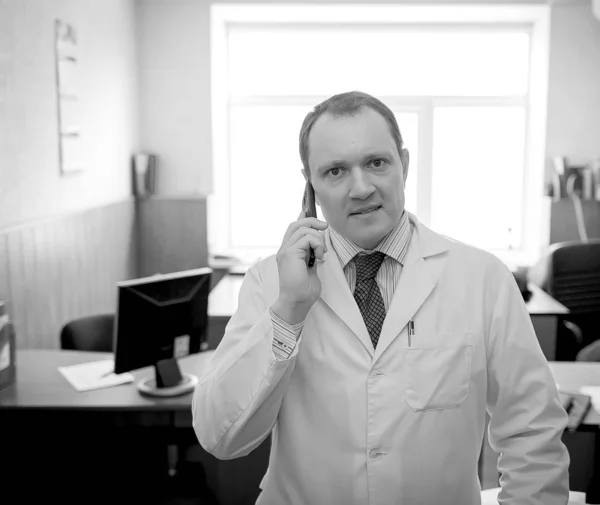 Молодой привлекательный врач в белом халате говорит по телефону — стоковое фото