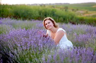 Beyaz elbiseli genç bir kadın lavanta tarlasında yürüyor.