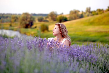 Beyaz elbiseli genç bir kadın lavanta tarlasında yürüyor.