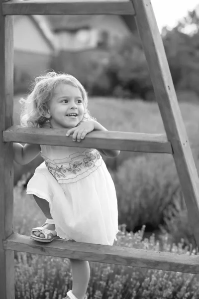 穿着白衣的小女孩爬上了小木屋里的木楼梯 — 图库照片