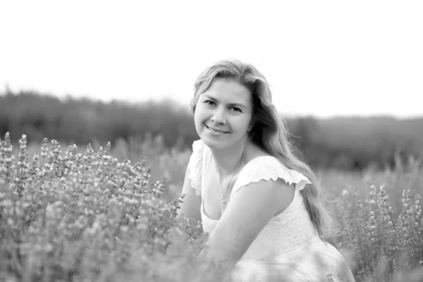 Una joven en un vestido blanco camina en un campo de lavanda — Foto de Stock