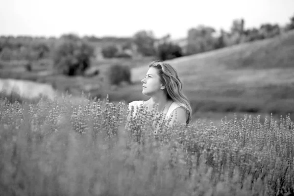 En ung kvinna i vit klänning går på ett lavendelfält — Stockfoto