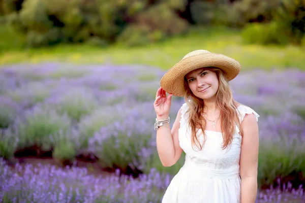 Jovem mulher em um chapéu de palha e passeios de sundress brancos em uma lavende — Fotografia de Stock