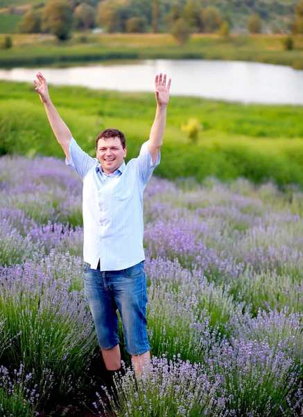 Een man in een blauw shirt en korte broek loopt in een lavendelveld — Stockfoto