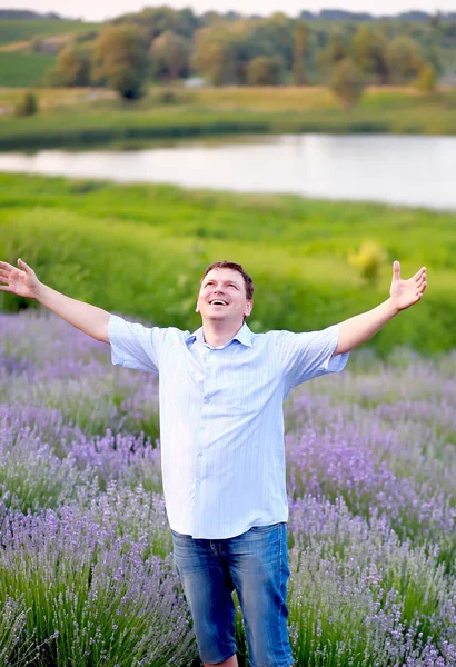 Un hombre con una camisa azul y pantalones cortos camina en un campo de lavanda — Foto de Stock