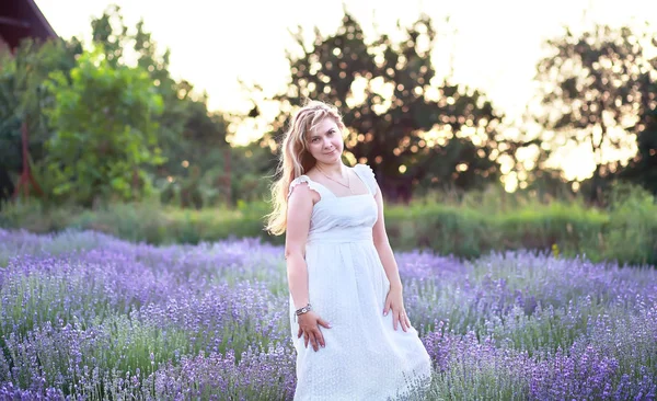 a young woman in a white sundress walks in a lavender field
